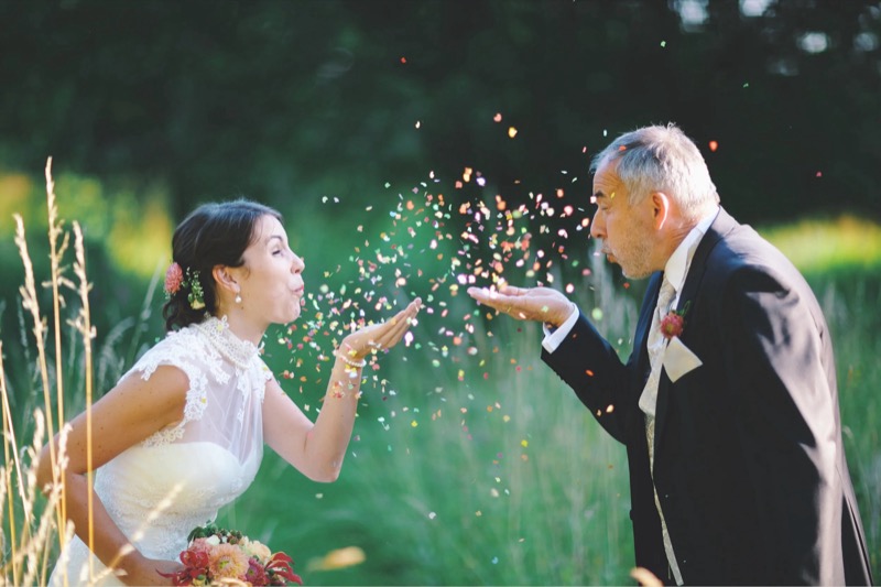Braut und Vater pusten Konfetti in die Luft