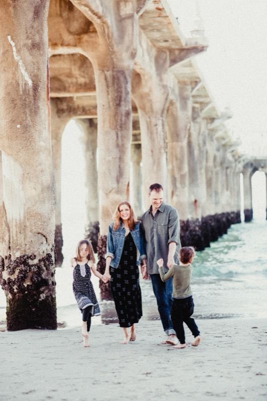 Familie läuft Hand in Hand unter einem Pier am Strand