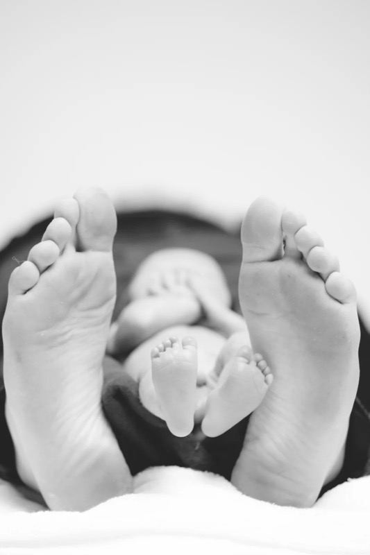 Babyfüße zwischen den Füßen der Eltern, Schwarzweiß