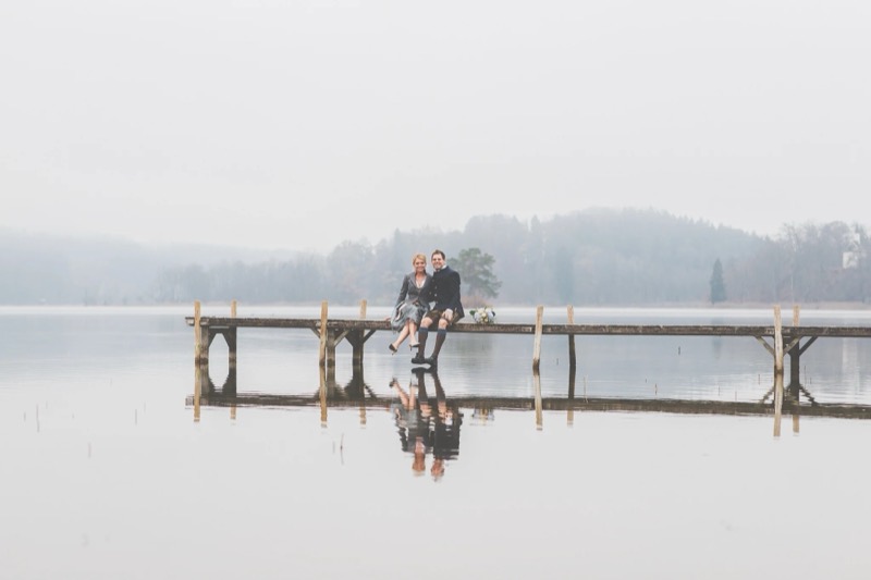 Brautpaar auf einem Steg im Nebel über dem See