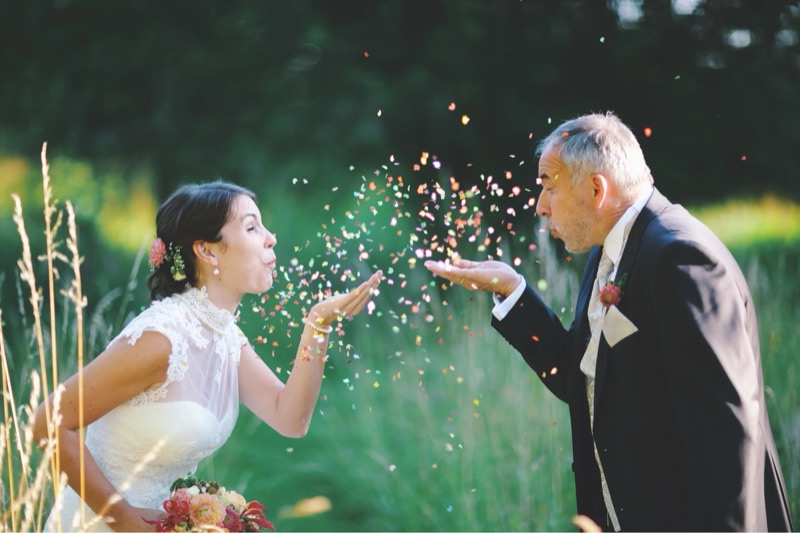 Braut und Vater pusten sich Konfetti zu